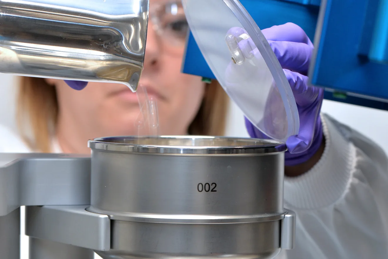 Farmacêutico de pesquisa adicionando ingredientes farmacêuticos à máquina de preenchimento e vedação de cápsulas duras CFS 1200 no laboratório Innovaform